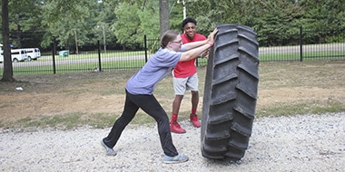 female student flipping over a large tire