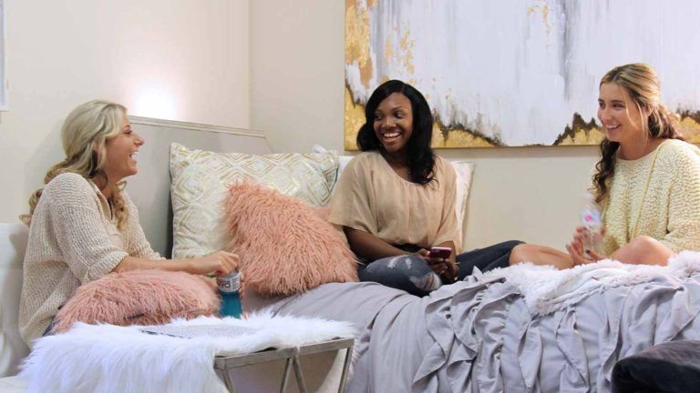 three female students laughing in dorm room