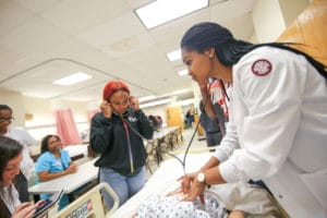 student listens for a heartbeat in a manikin
