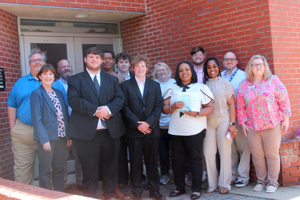 Group photo of Academic Dean Melissa Buie, students Andrew Kilpatrick and Carter Smith, honoree Lashonda McDonald-Graham, Hinds Instructors Dr. Shannon Anderson and Sarah Nichols; back from left, Hinds Instructors Eric Bobo and Stephen Wedding, students Braylen Jones and Landon Womack and Hinds Instructors Brandy Rowland, Matt Ansley and Jason Stewart.